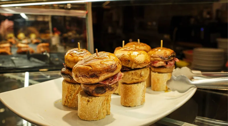Grilled mushroom and cured ham pintxos served on rounds of baguette