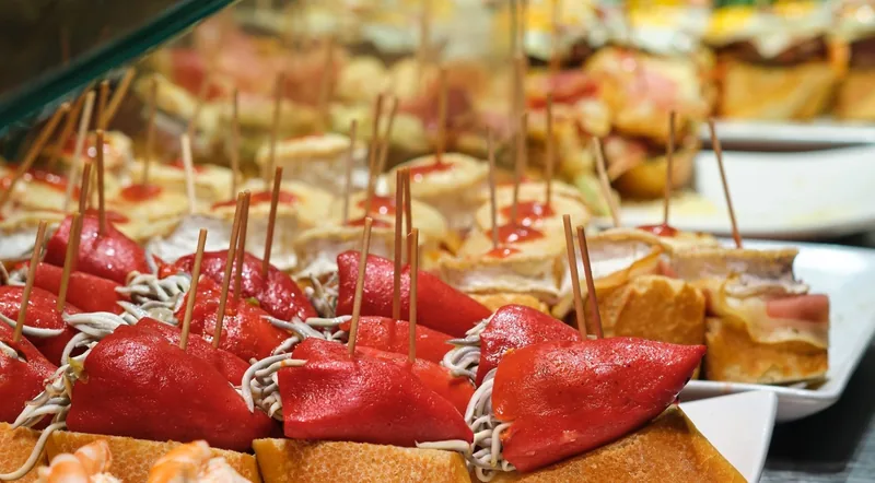 Piquillo pepper and baby eel pintxos on bread with wooden skewers at a Basque bar