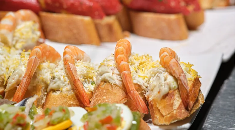 Prawn and crab pintxos on sliced baguette on a bar counter in San Sebastian