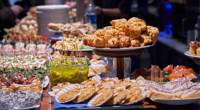 A long bar counter loaded with pintxos in the evening