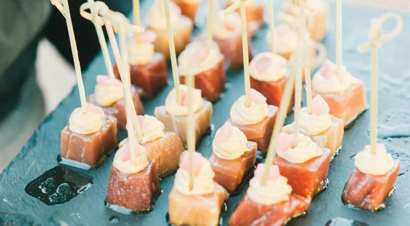 Cubes of marinated tuna topped with cream on a slate serving board